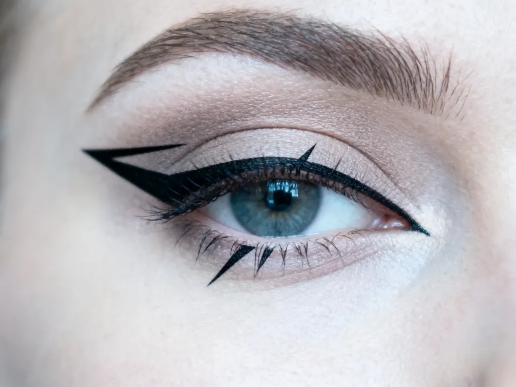 Precyzyjna, czarna kreska w stylu graphic eyeliner na powiece z neutralnym cieniem i długimi rzęsami.