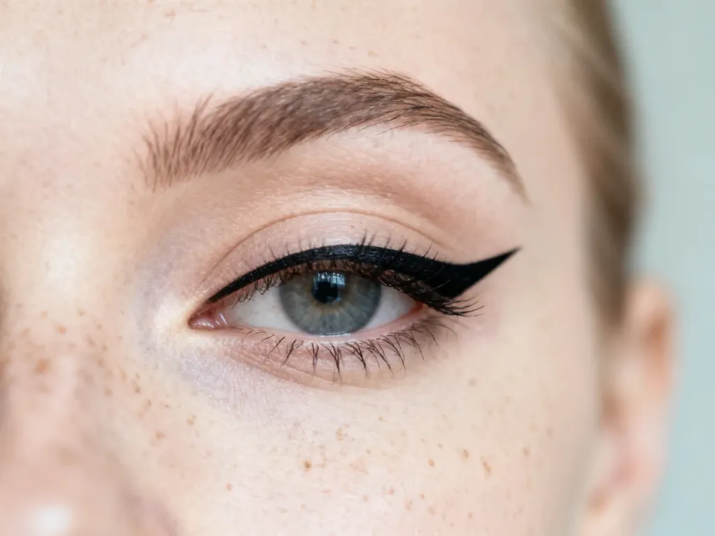 Zbliżenie na oko z precyzyjnie wykonaną czarną kreską typu eyeliner w stylu jaskółki.